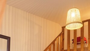 A wooden staircase leading to a landing with a television and storage shelves.