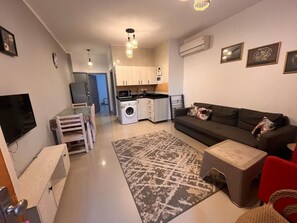 Een compacte woonruimte met een kitchenette, een eethoek, een bank en een televisie.