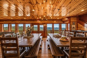 Un intérieur en bois avec une longue table et des bancs, de grandes fenêtres donnant sur la montagne et un panneau indiquant la sortie.