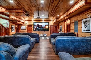 Ein Holzinterieur mit einer zentralen Sitzecke, einem Wandfernseher und gerahmten Bildern an den Wänden.