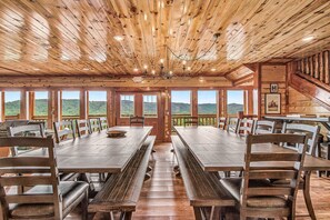 A wooden interior with a large dining table, benches, and multiple windows offering a view of the outdoors. - Wheelchair Accessible - 7000sqft + Incredible Views + Heated Indoor Pool-Hot tub (Pigeon Forge)