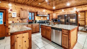 Una cocina amplia con gabinetes de madera, encimeras de granito y electrodomésticos de acero inoxidable, además de una isla central.