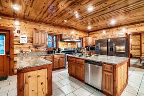 A spacious kitchen with wooden cabinets, granite countertops, stainless steel appliances, and a central island. - Sleeps 40 | 12BR, Indoor Pool, 2 Hot Tubs (Pigeon Forge)