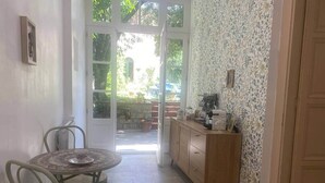 Ein Zimmer mit Esstisch, Stühlen, einem Holzschrank und einer Tür, die zu einem Außenbereich führt.