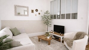 A living room with a sofa, a coffee table, a TV, and a plant. - Apartment with Private Garden Oasis in Central Carcassonne (Carcassonne)