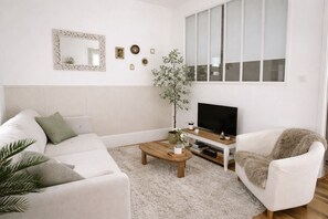 Een woonkamer met een bank, een salontafel, een televisie en een plant.