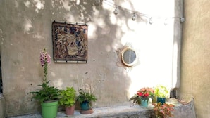 A stone ledge with potted plants, a metal watering can, a decorative mirror, and a tapestry on the wall. - Apartment with Private Garden Oasis in Central Carcassonne (Carcassonne)