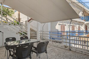 An outdoor seating area with a table and chairs, a white awning, and a blue fence. - Apartment 'Kagias  1' with Sea View, Wi-Fi and Air Conditioning (Petalidi)