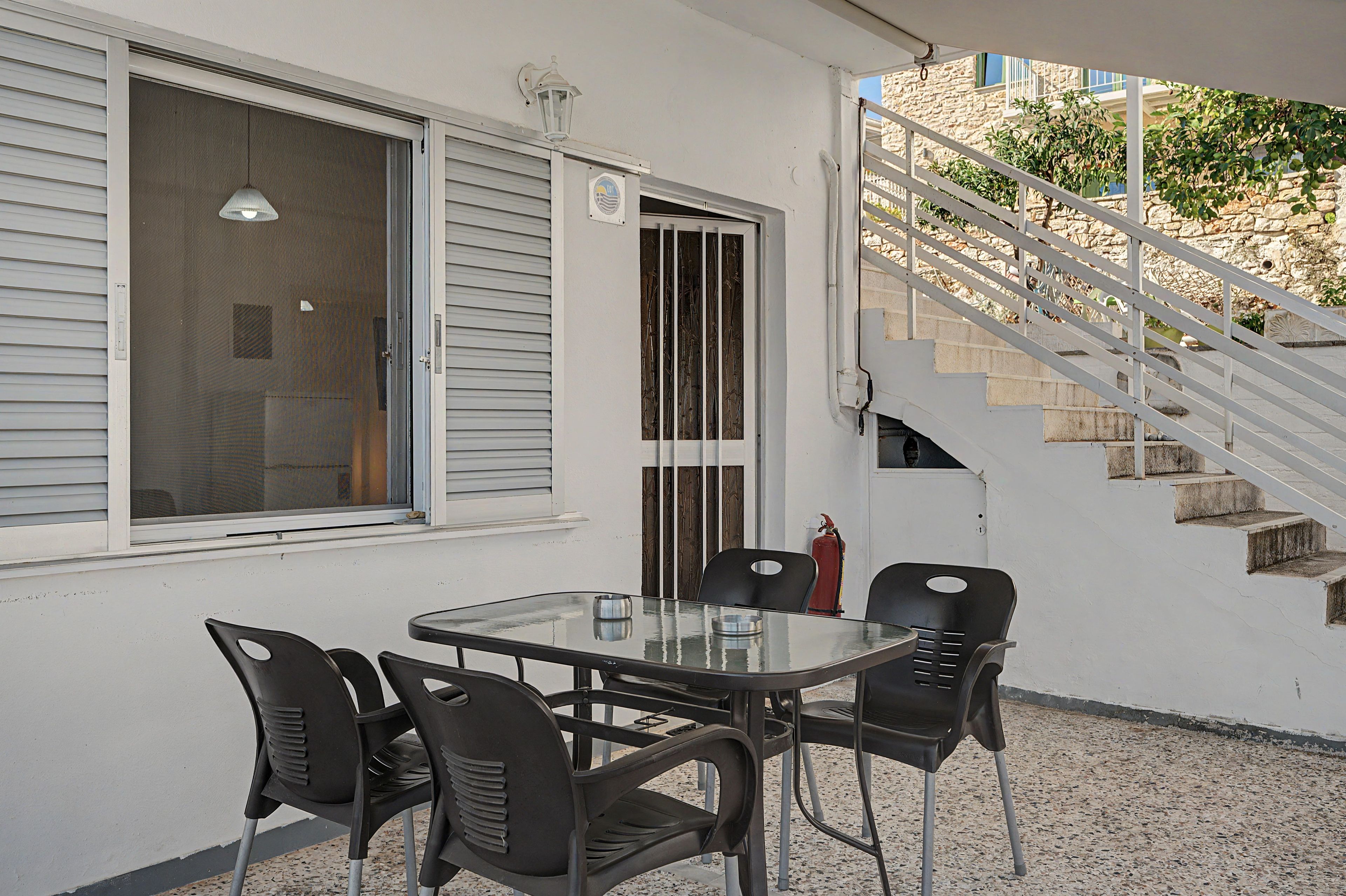 Une terrasse avec une table et des chaises, un extincteur et un escalier.
