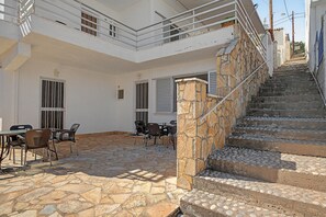 A building with a stone staircase, outdoor seating area, and a balcony.