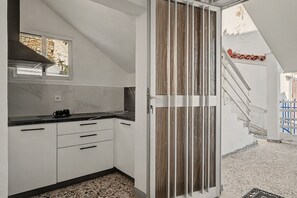 A modern kitchen with white cabinetry, a black countertop, and a view of a garden through a window. - Apartment 'Kagias  1' with Sea View, Wi-Fi and Air Conditioning (Petalidi)