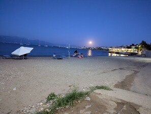 A beach with umbrellas, lounge chairs, and a view of the sea and distant boats. - Apartment 'Kagias  2' with Sea View, Wi-Fi and Air Conditioning (Petalidi)