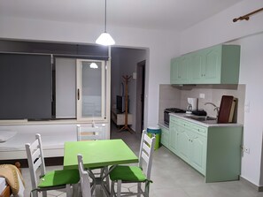 A compact living space with a dining table, chairs, a kitchenette, and a wardrobe.