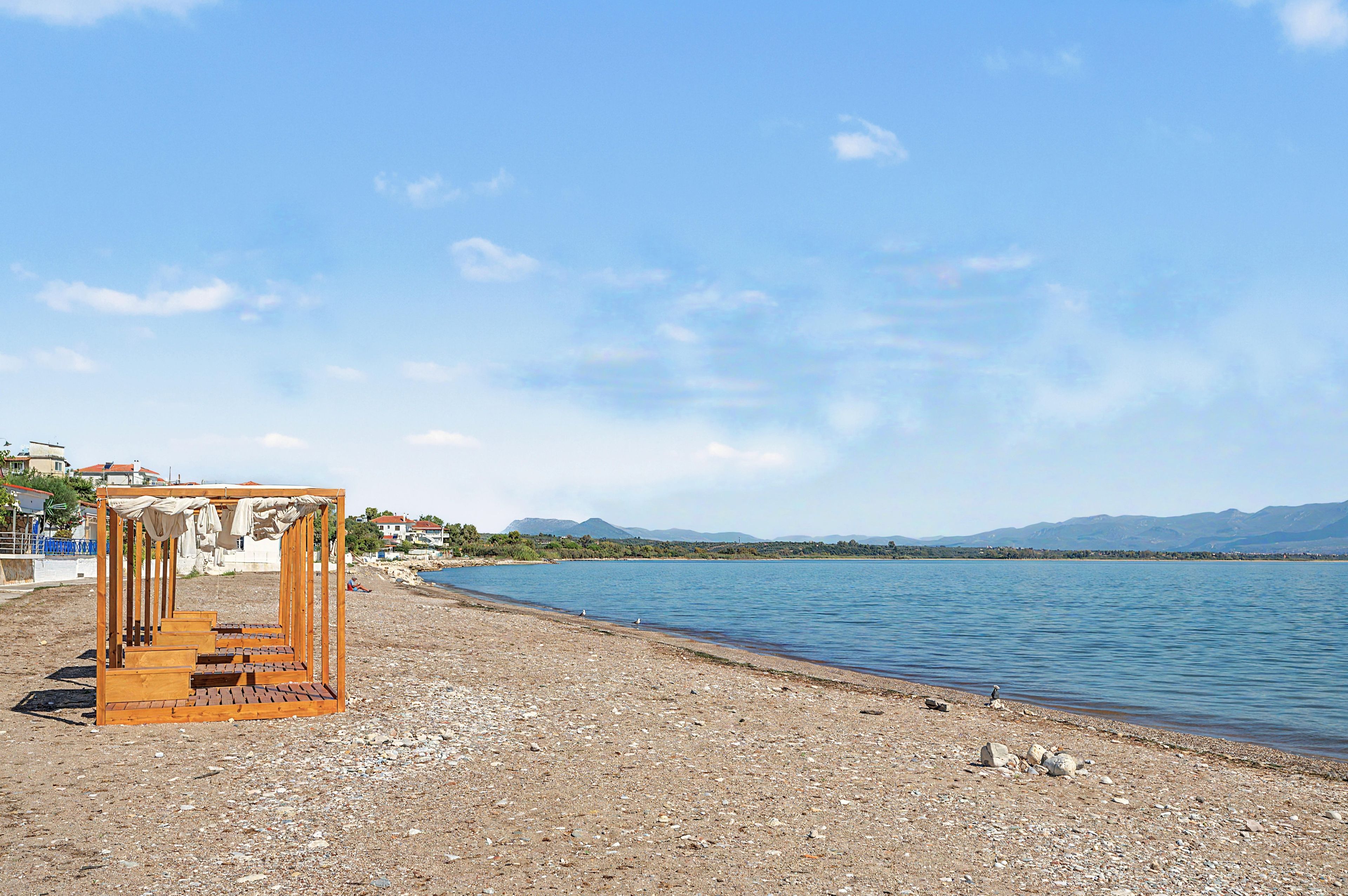 A beach with a wooden structure, a pebble beach, and a calm sea.