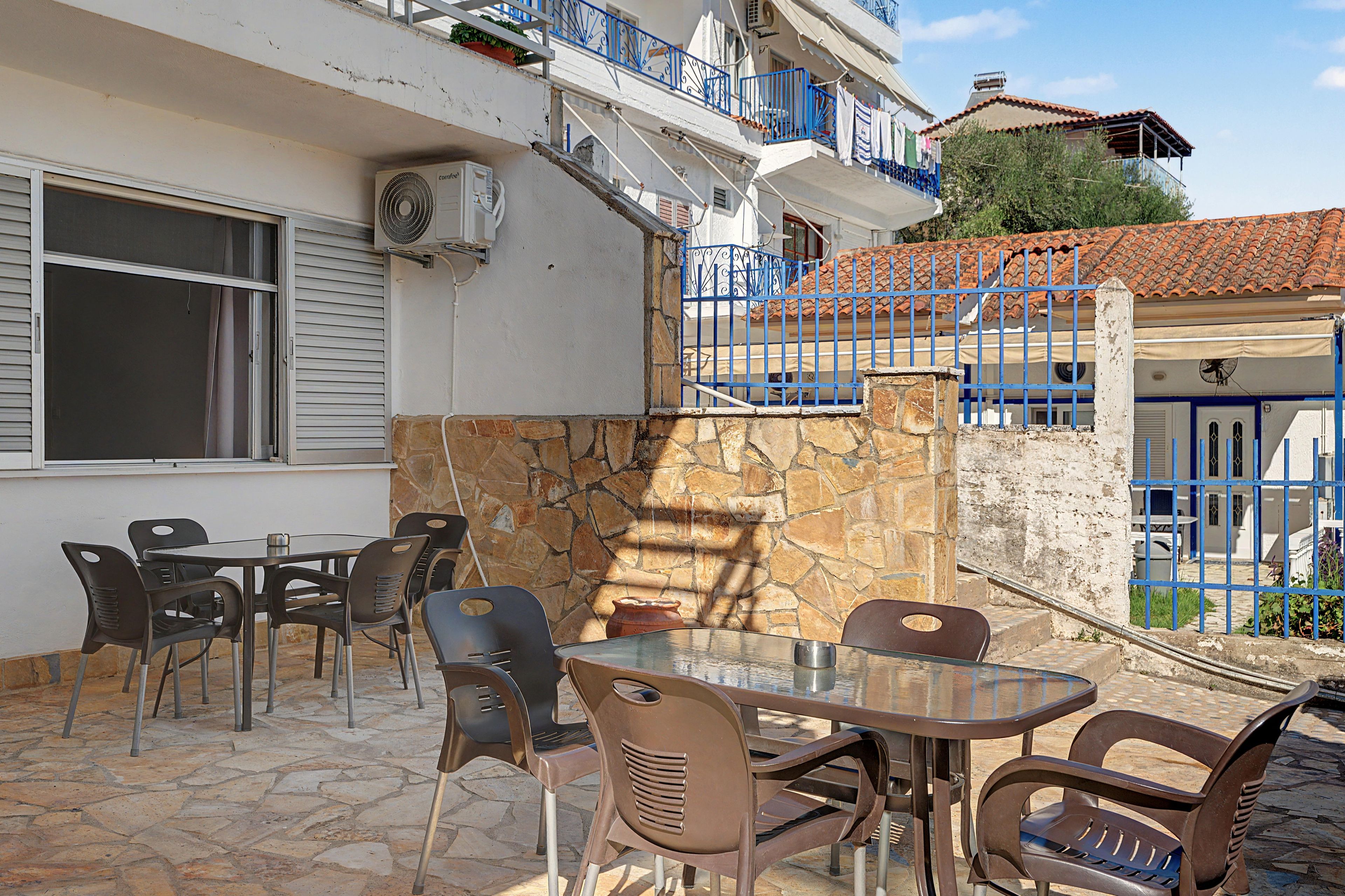 An outdoor seating area with a stone wall, a table, and chairs.