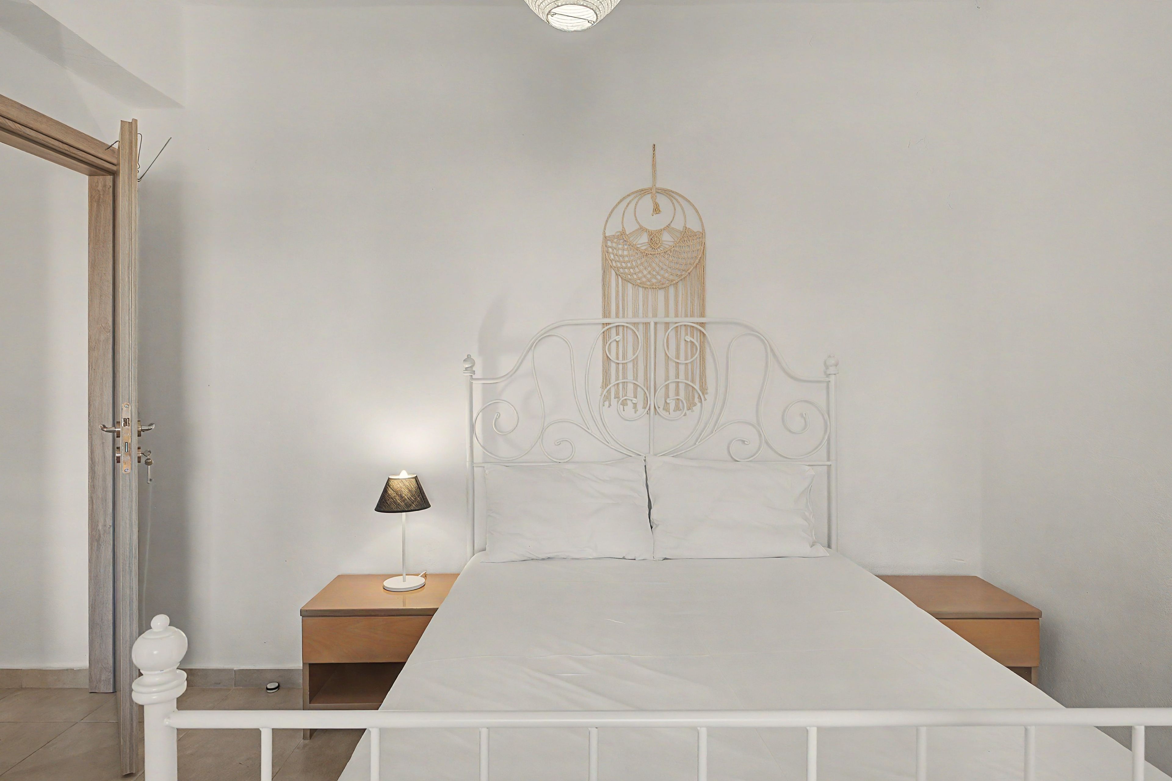 Une chambre à coucher avec un lit en métal blanc, une table de chevet avec une lampe et une décoration murale au-dessus du lit.