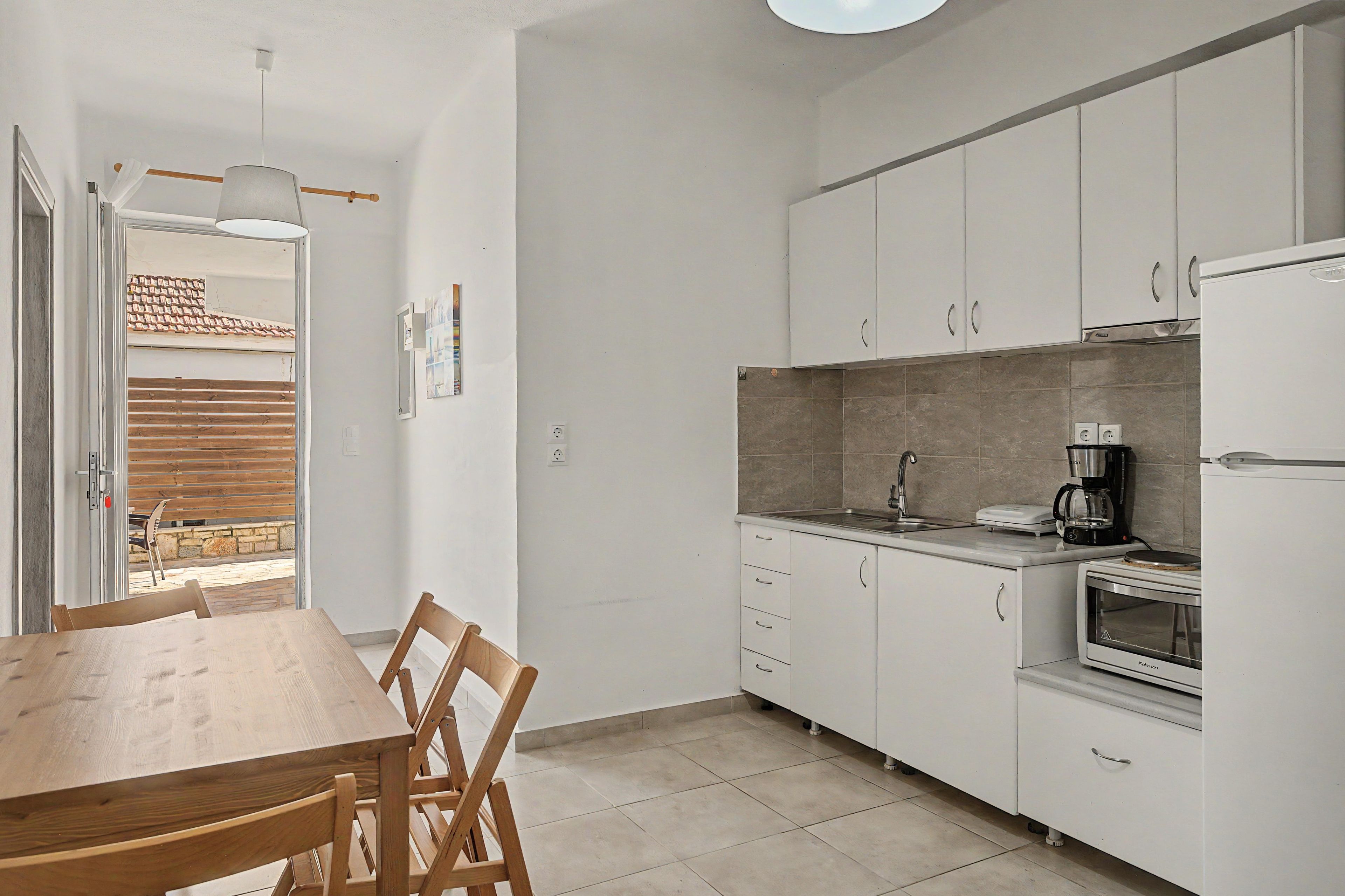 A compact kitchen with white cabinets, a wooden dining table, and a built-in oven.