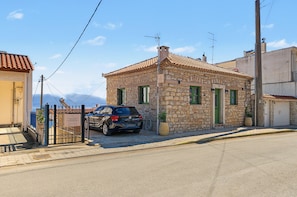 A stone building with a tiled roof, a parked car, and a gated entrance. - Apartment 'Kagias  4' with Sea View, Wi-Fi and Air Conditioning (Petalidi)