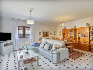 Una sala de estar con sofá, mesa de centro, televisor y un comedor con sillas y un aparador.