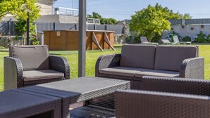 Een terras met rieten meubilair en een pergola.