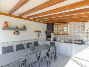 A modern kitchen with a built-in stove, wooden cabinets, and a dining area with a table and chairs.