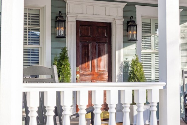A porch with a wooden door, white railings, and two lanterns. - 5BR Historic Downtown (Edenton)