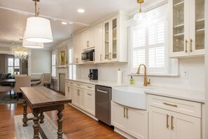A kitchen with white cabinetry, a dining table, and a chandelier. - 5BR Historic Downtown (Edenton)
