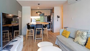 Una cocina moderna con comedor, un sofá con cojines y un televisor de pantalla plana.