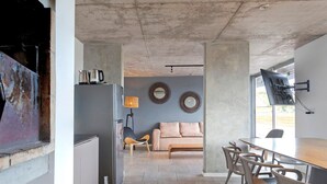 Una cocina moderna con refrigerador, cafetera y lámpara. Hay un comedor con mesa y sillas.
