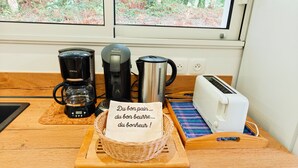 Un plan de travail de cuisine avec une machine à café, un grille-pain et un petit mot posé sur une planche à découper.