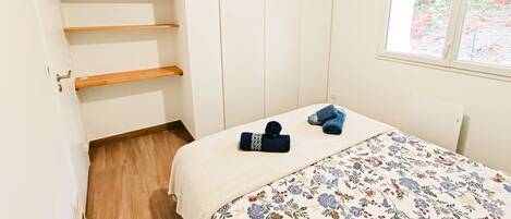 A bedroom with a bed, a wardrobe, a window with a view, and a door.