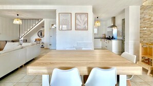 A modern kitchen with white cabinets, a wooden dining table, and two white chairs. - Le Jardin Bleu, 6-person villa swimming pool (Saint-Geniès-de-Malgoirès)