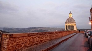 A stone bridge with a paved road, a dome-shaped building in the distance, and a clear sky. - A retreat in the baroque heart of Ragusa Ibla (Ragusa)