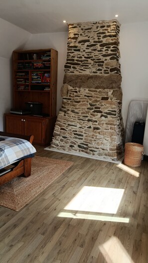 A room with a stone wall, wooden furniture, a bed, and a bookshelf. - Country house with fireplace, right next to trails. Pets welcome! (Mégrit)