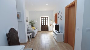 Un soggiorno con divano, televisore e una porta in legno.