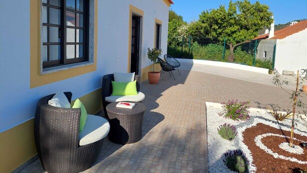 Un edificio con patio, arredi in vimini e un piccolo giardino.