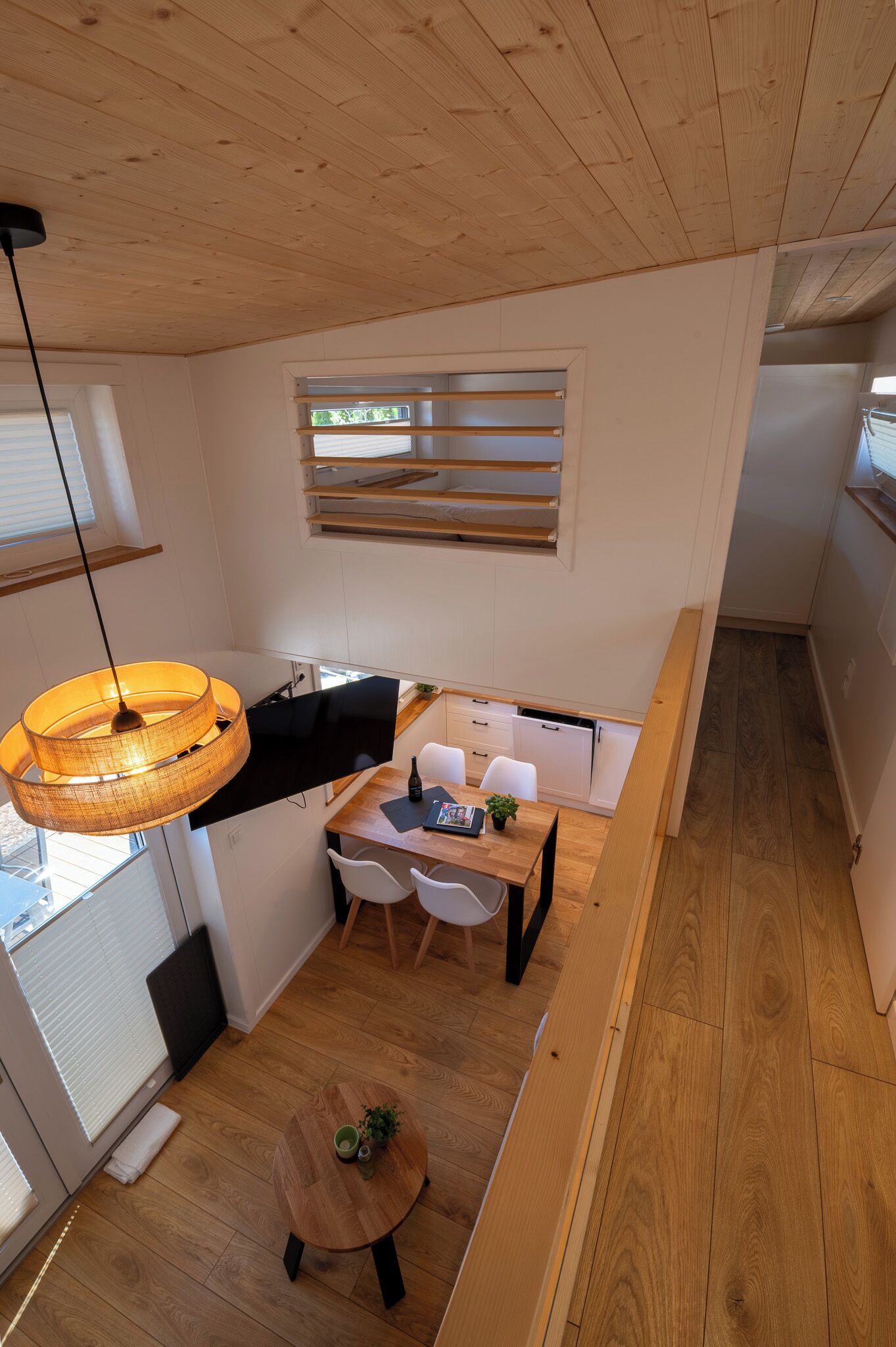 Une cuisine moderne avec un coin repas, un plancher en bois et un luminaire suspendu.