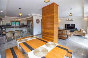 Una cocina moderna con comedor, una pared de acento de madera y un televisor en la sala.