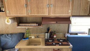 Una kitchenette compacta con lavabo, estufa y armarios de almacenamiento.