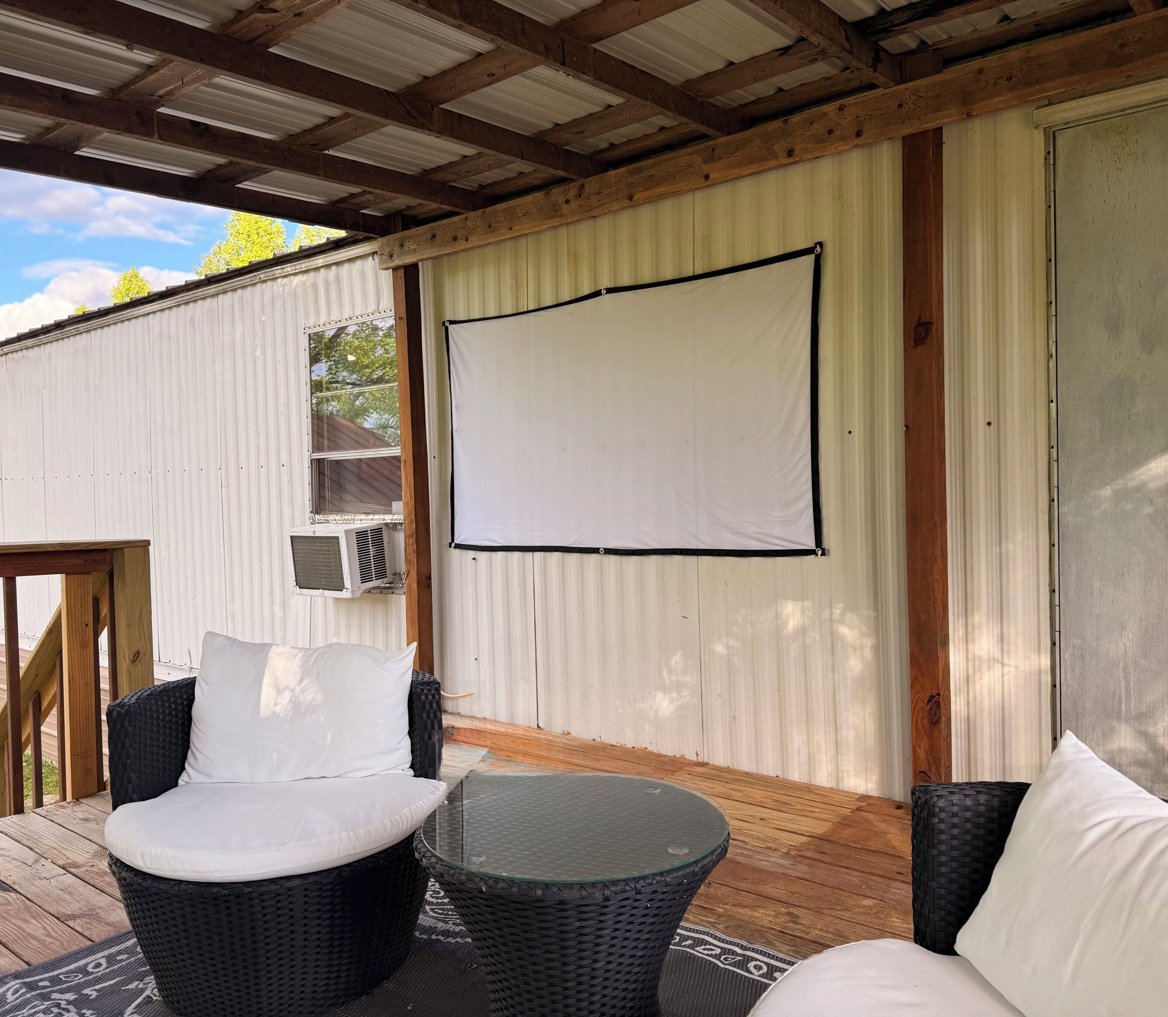 A covered outdoor seating area with wicker furniture and a white screen.