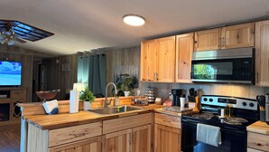 A modern kitchen with wooden cabinets, a stainless steel microwave, a stove, and a sink.