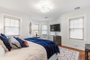 Una camera da letto con un letto, una TV, un comò e una sedia.