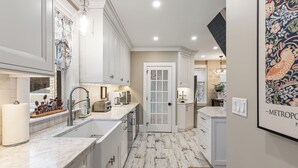 Una cocina moderna con armarios blancos, encimera de mármol y suelo de estilo rústico.