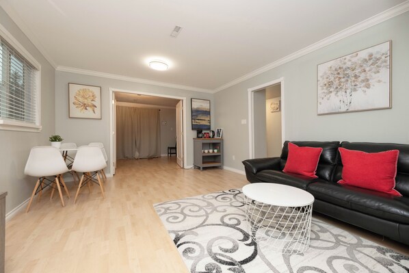 A living room with a black leather sofa, white coffee table, and a patterned rug.