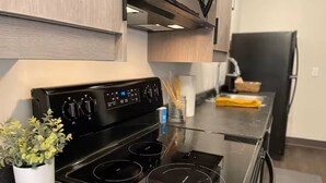 Une cuisine moderne dotée d’une plaque de cuisson en verre, d’appareils électroménagers en acier inoxydable et de meubles en bois.