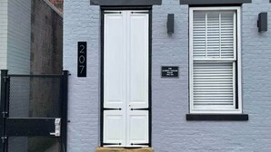 Un edificio de dos pisos con una puerta blanca y una ventana con persianas.