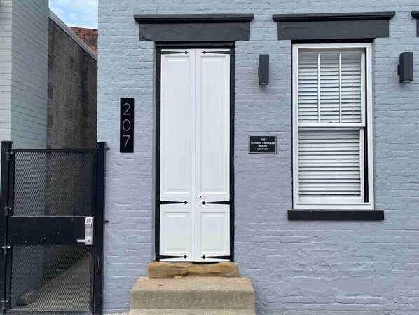Un bâtiment à deux étages avec une porte blanche et une fenêtre équipée de stores.
