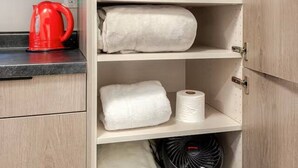 Una cocina con hervidor, toallas y ventilador.