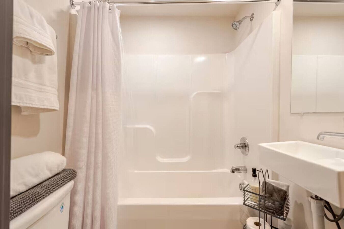 A bathroom with a bathtub, a shower, a sink, and a towel rack.