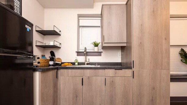 Una cocina moderna con armarios de madera clara, un refrigerador negro y una ventana sobre el fregadero.